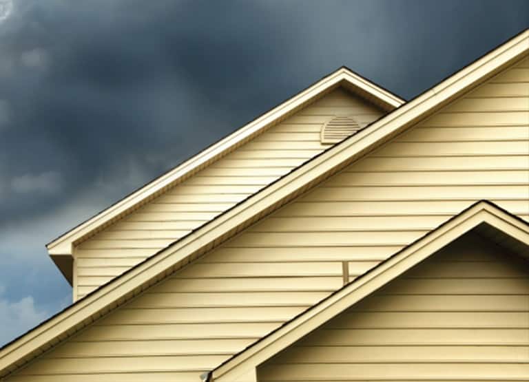 House with Yellow Siding and Storm Clouds In the Background